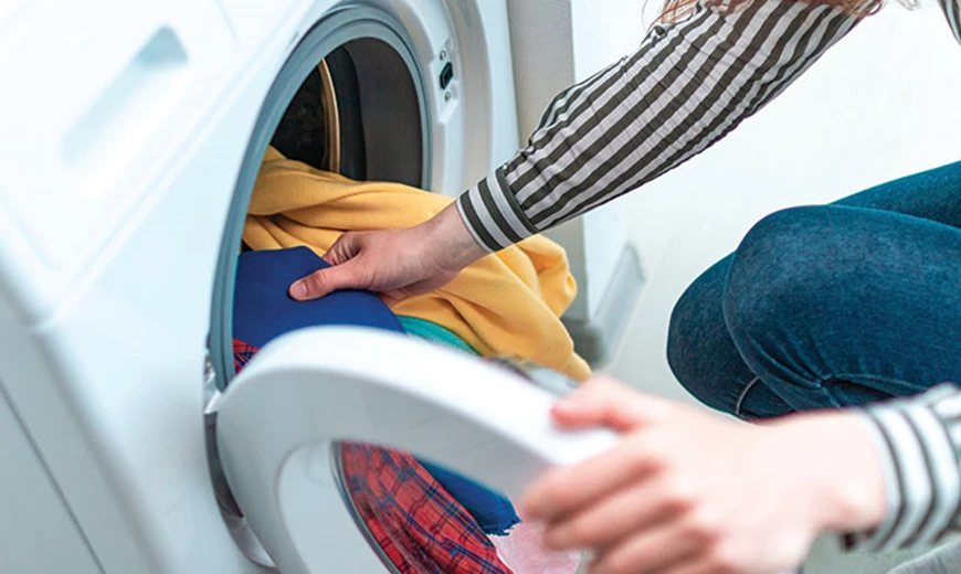 Frau füllt Waschmaschine Auch über Textilien ist Hautpilz ansteckend