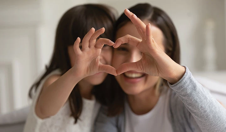 Mutter und Tochter zeigen ein Herz mit den Händen Der Candida albicans kann Jung und Alt befallen