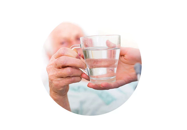 Pflegerin reicht Patient Wasser  Ernährung bei Dekubitus